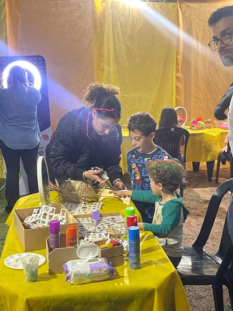 Crianças participando de atividades recreativas em mesa de artesanato